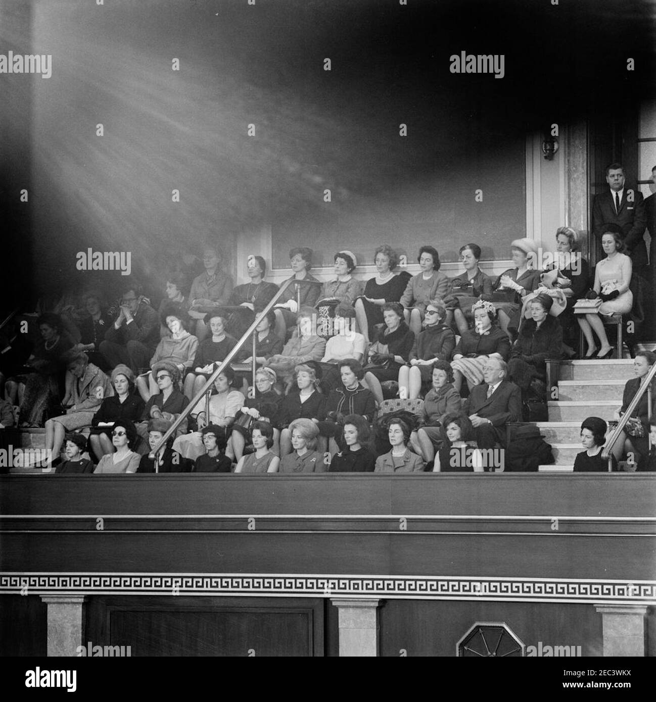Stato dell'Unione Indirizzo, 12:33 PM. La First Lady Jacqueline Kennedy e altri ascoltano il presidente John F. Kennedy nel suo discorso annuale al Congresso sullo Stato dell’Unione. Anche nella foto: Segretario personale del presidente Kennedyu2019s, Evelyn Lincoln; primo segretario stampa Ladyu2019s, Pamela Turnure; Erma Lee Webb Udall (moglie del segretario dell'interno Stewart Udall); Jane Shields Freeman (moglie del segretario dell'agricoltura Orville Freeman); Principessa Lee Radziwill (sorella della prima Signora); Janet Lee Auchincloss (madre della prima Signora); Margaret Craig McNamara (moglie del Segretario o Foto Stock