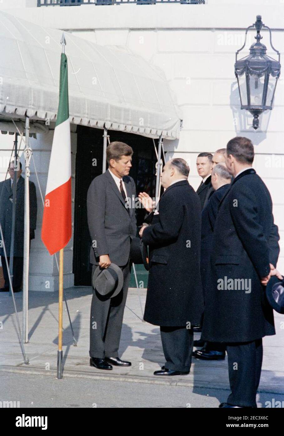 Cerimonia di arrivo del primo Ministro italiano Amintore Fanfani, ore 11:15. Il Presidente John F. Kennedy (cappello) parla con l'Ambasciatore del Nicaragua e il Decano del corpo Diplomatico, il Dott. Guillermo Sevilla-Sacasa, alle cerimonie di arrivo del primo Ministro italiano Amintore Fanfani. Il Direttore degli Affari dell'Europa Occidentale del Dipartimento di Stato, Francis E. Meloy, si trova in background (a destra di Sevilla-Sacasa); l'Assistente Capo del protocollo per le visite e gli eventi pubblici, Samuel L. King (di ritorno alla telecamera), si trova all'estrema destra. Portico Sud, Casa Bianca, Washington, D.C. Foto Stock