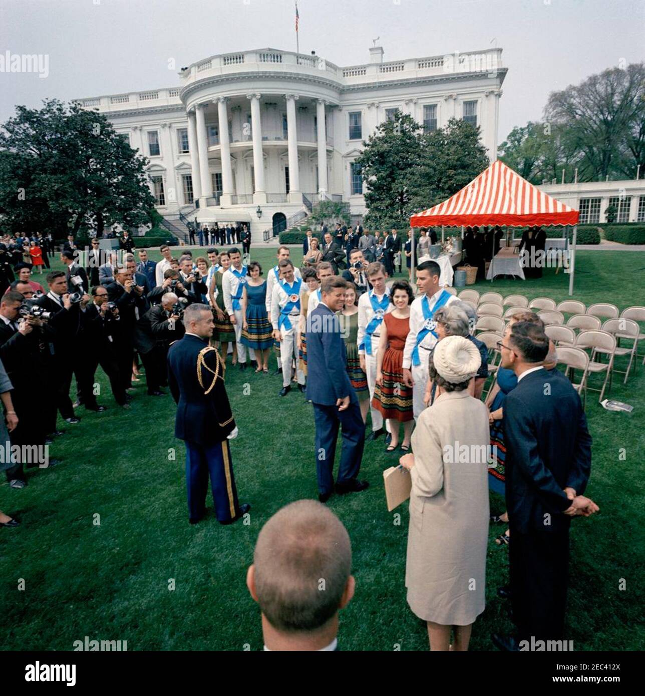 First Lady Jacqueline Kennedyu0027s (JBK) programma musicale per giovani, 14:10. Il presidente John F. Kennedy (centro) saluta i membri del Berea (Kentucky) College Country Dancer sul prato sud della Casa Bianca, Washington, D.C.; i fotografi e altri osservano. Il gruppo di danza ha suonato come parte della sesta puntata di First Lady Jacqueline Kennedyu2019s Musical Programs for Youth by Youth. Foto Stock