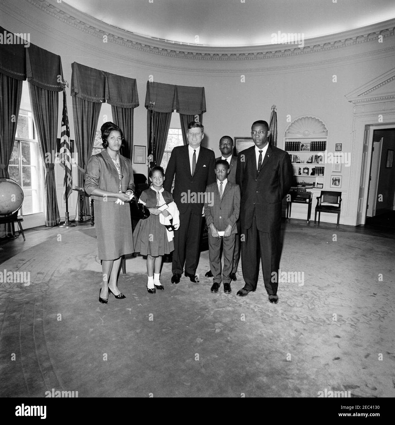 Visita di Myrlie Evers, vedova di Medgar Evers, e la famiglia. Il presidente John F. Kennedy (centro) visita con Myrlie Evers (all'estrema sinistra), vedova del leader dei diritti civili, Medgar Evers. Anche nella foto: Reena e Darrell Evers, figli di Medgar e Myrlie; Charles Evers (a destra), fratello di Medgar. Un uomo non identificato sta dietro a destra. Ufficio ovale, Casa Bianca, Washington, D.C. Foto Stock