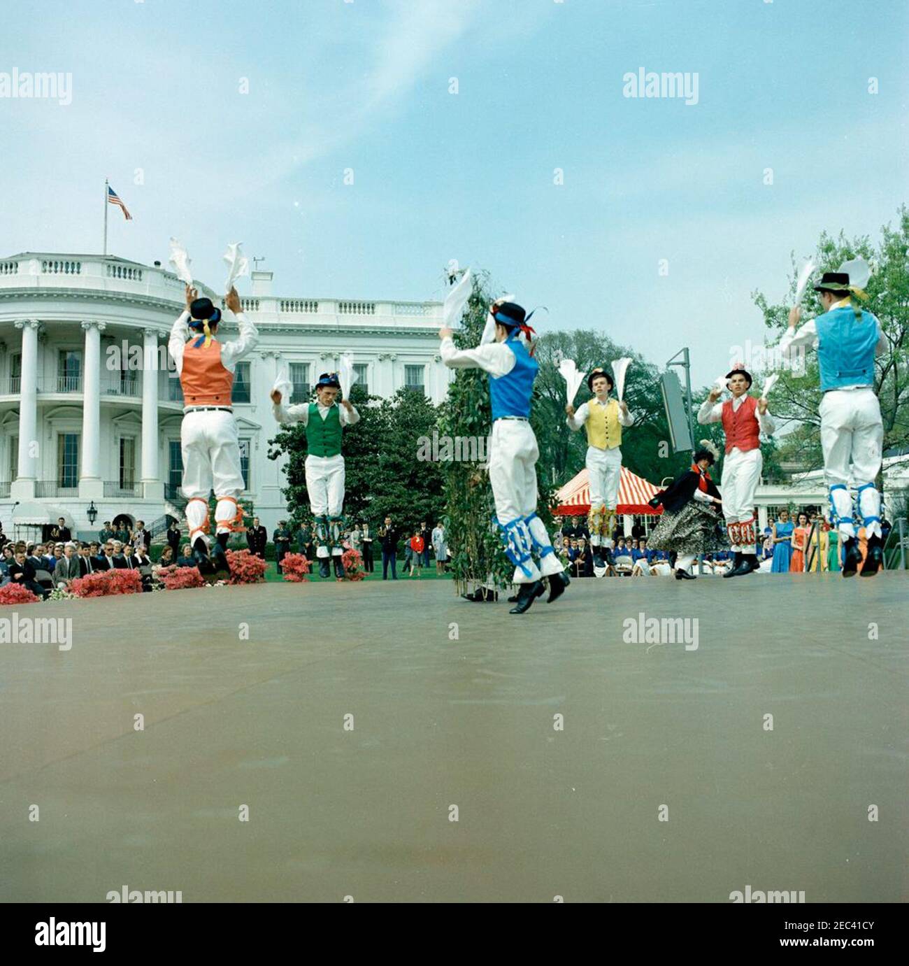 First Lady Jacqueline Kennedyu0027s (JBK) programma musicale per giovani, 14:10. I membri del Berea (Kentucky) College Country Dancers si esibiscono sul palco durante la sesta puntata di First Lady Jacqueline Kennedyu2019s Musical Programs for Youth by Youth. Musicisti della Central Kentucky Youth Symphony Orchestra sono seduti a destra del palco; l'orchestra si è esibita anche durante l'evento che si è tenuto sul South Lawn of the White House, Washington, D.C. Foto Stock