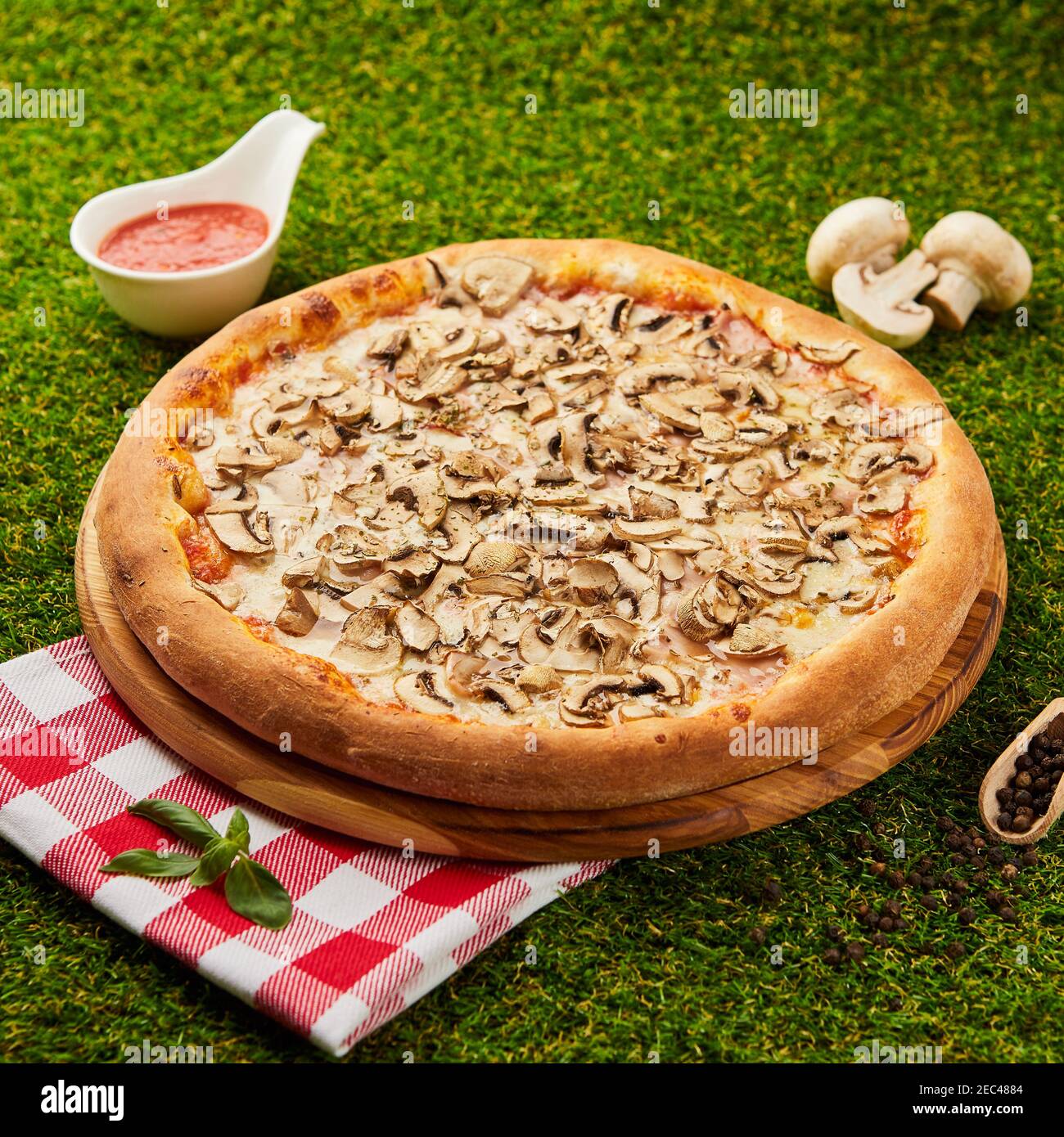 Deliziosa pizza con funghi e ronzio su fondo verde erba Foto Stock