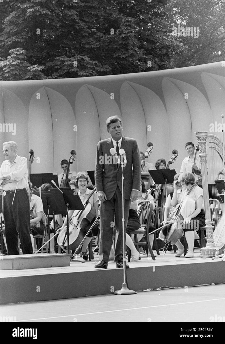 First Lady Jacqueline Kennedyu0027s (JBK) programma musicale per la gioventù, 10:35. Il presidente John F. Kennedy (ai microfoni) commenta la quarta serie di programmi musicali per giovani della First Lady Jacqueline Kennedyu0027s. I membri della National High School Symphony Orchestra del National Music Camp di Interlochen, Michigan, siedono sulla tribuna; direttore d'orchestra e presidente del National Music Camp, il Dr. Joseph E. Maddy (armi incrociate), si trova all'estrema sinistra. South Lawn, Casa Bianca, Washington, D.C. Foto Stock