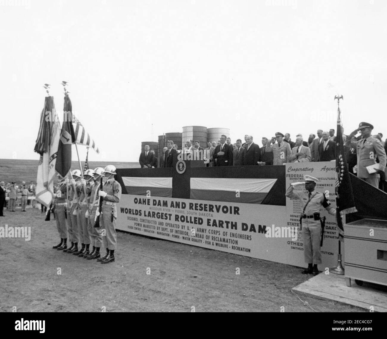 Viaggio negli stati occidentali: Pierre, South Dakota (Oahe Dam), 10:25. Il presidente John F. Kennedy (a sinistra del leggio) e altri si trovano sulla piattaforma del parlante 0027 durante la cerimonia di dedicazione della diga e del serbatoio di Oahe, sulle rive del fiume Missouri, vicino a Pierre, South Dakota. Altri sulla piattaforma includono: Segretario dell'interno, Stewart L. Udall; candidato senatoriale degli Stati Uniti dal Dakota del Sud, George McGovern; Governatore del Dakota del Sud, Archie M. Gubbrud; Segretario dell'esercito, Cyrus R. Vance; Capo degli ingegneri dell'esercito, Tenente Generale Walter K. Wilson, Jr.; scultore, Korczak Ziolkowski; O. Foto Stock