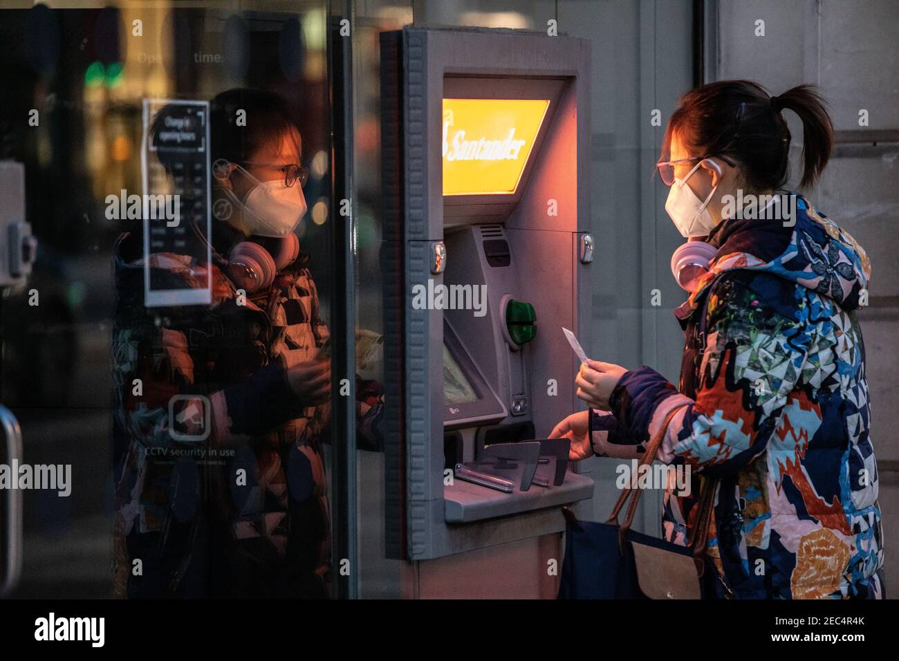 Donna che preleva denaro da un distributore di contanti della banca Santander a Londra, Inghilterra, Regno Unito Foto Stock