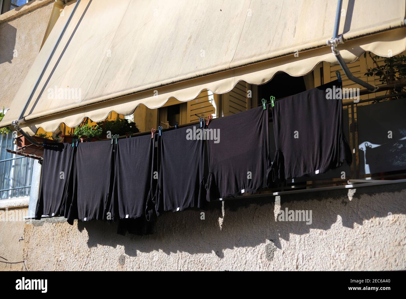 T-shirt nere da asciugare sul balcone della casa Foto Stock