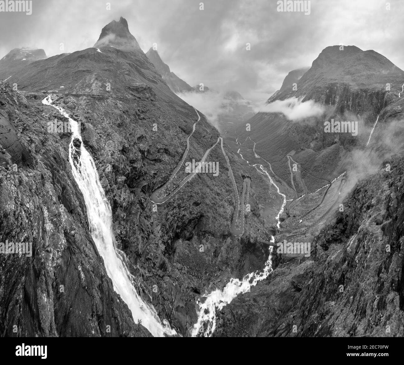 Scala di grigi. Summer Trollstigen serpente strada di montagna e la cascata Stigfossen vista dal Trolls Path Viewpoint, Norvegia. Foto Stock