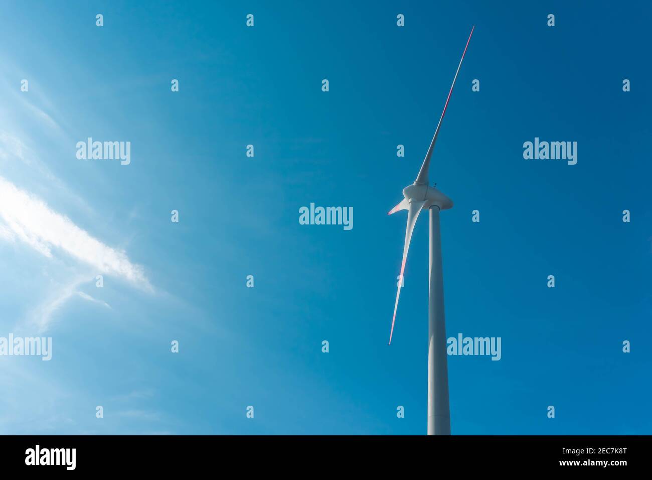 Aerogeneratore su sfondo blu con flusso di luce solare. Concetto di energia pulita e rinnovabile Foto Stock