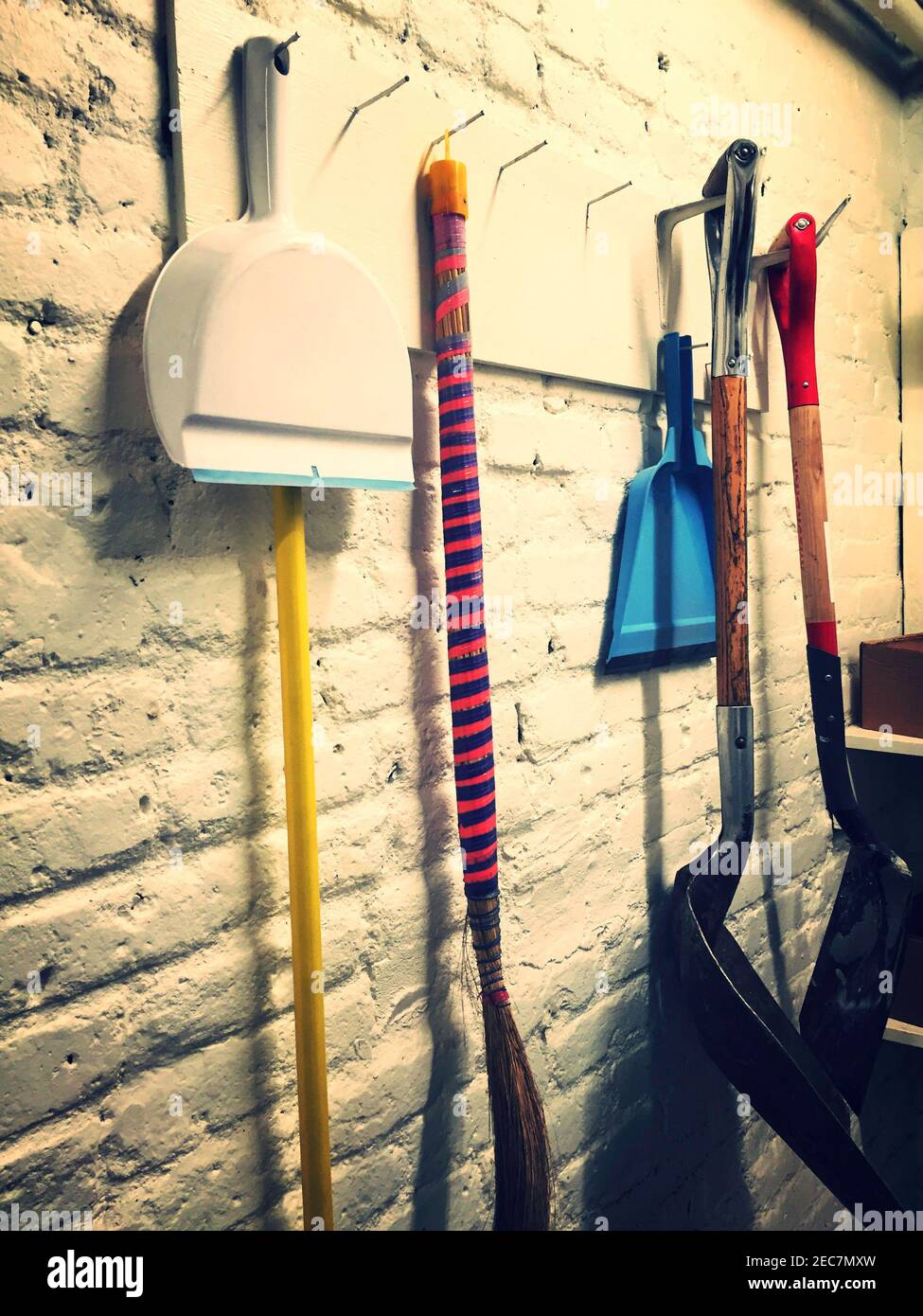 Scopa e Dustpan impigliare su un muro di mattoni in un seminterrato residenziale, Stati Uniti Foto Stock