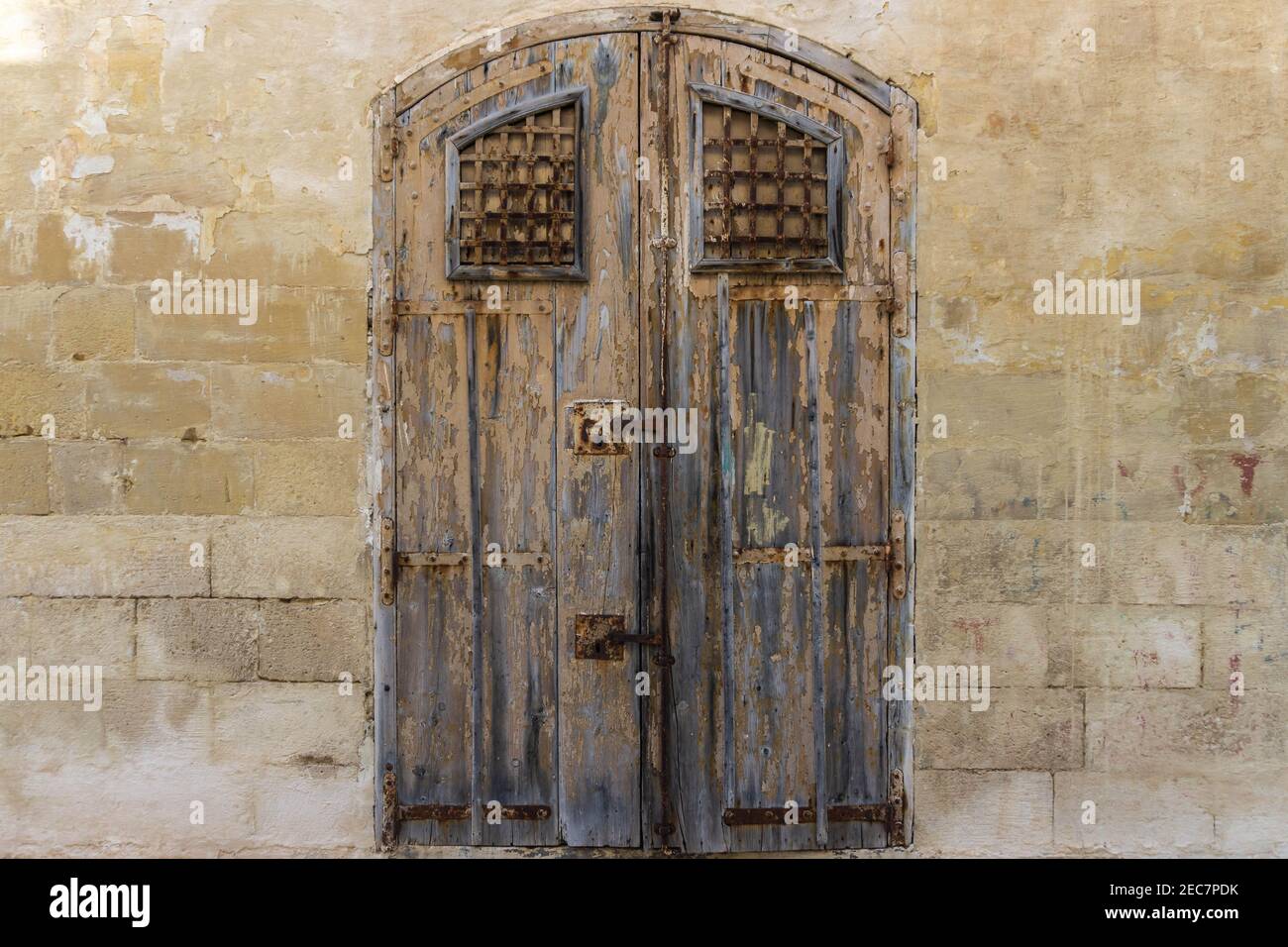 Vintage vecchio magazzino legno marrone verniciato porta con antico muro di mattoni di calcare. Vista frontale dei cancelli del magazzino abbandonato a Malta Foto Stock