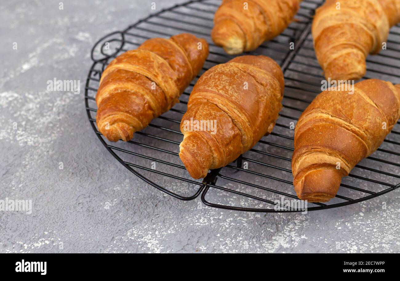 Croissant appena sfornati su griglia di raffreddamento. Tradizionale concetto di colazione francese Foto Stock
