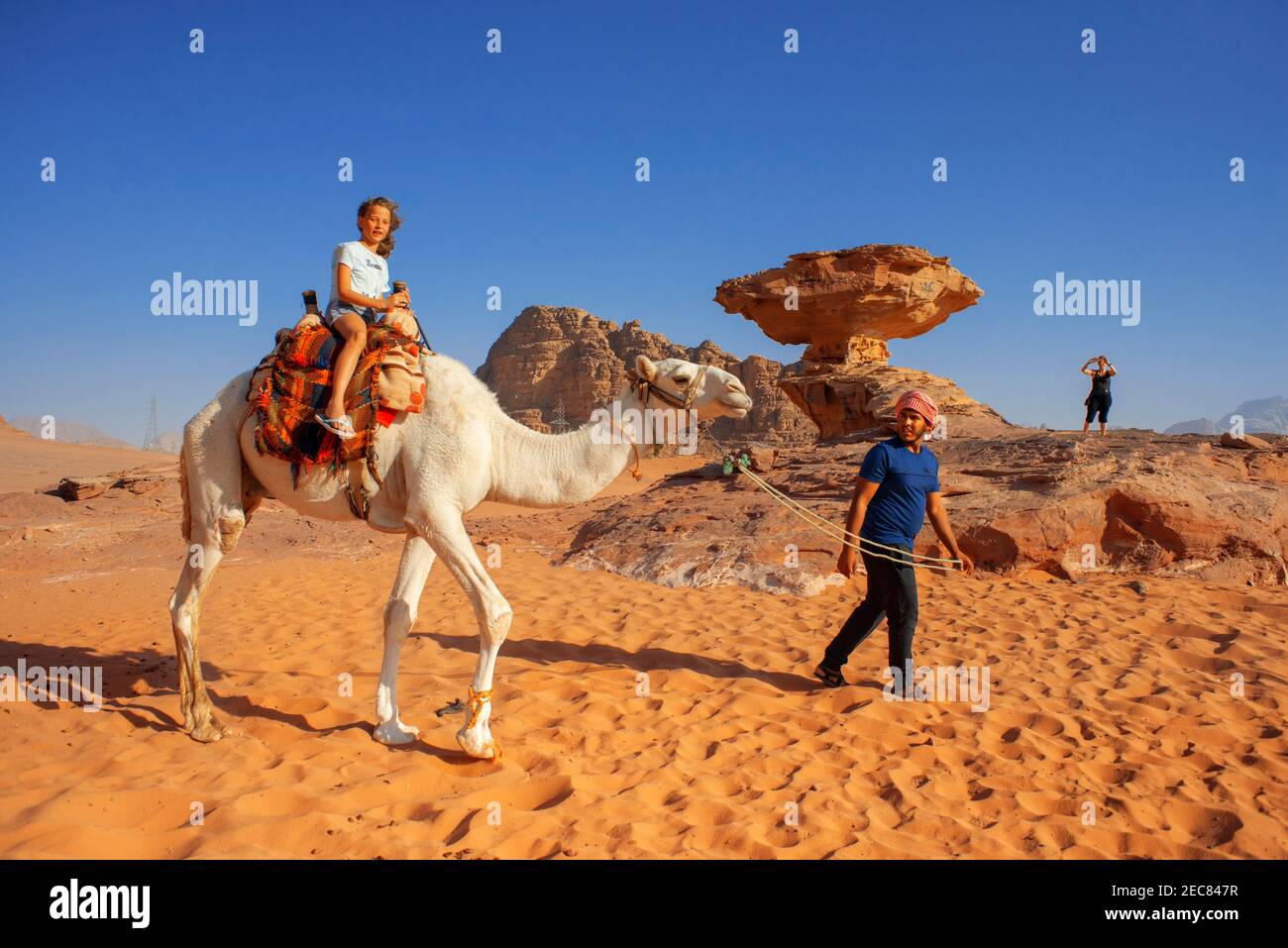 Ragazza turistica su un cammello di fronte alla roccia di funghi al Fetra Wadi Rum, Giordania Foto Stock