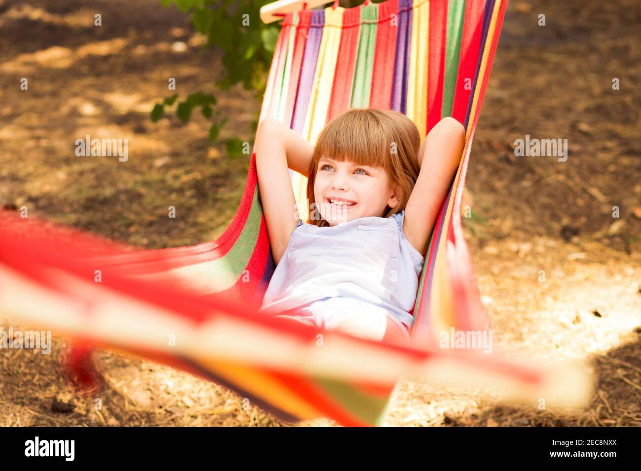 Vacanze estive. Bella bambina riposa in amaca colorata all'aperto nella foresta estiva Foto Stock