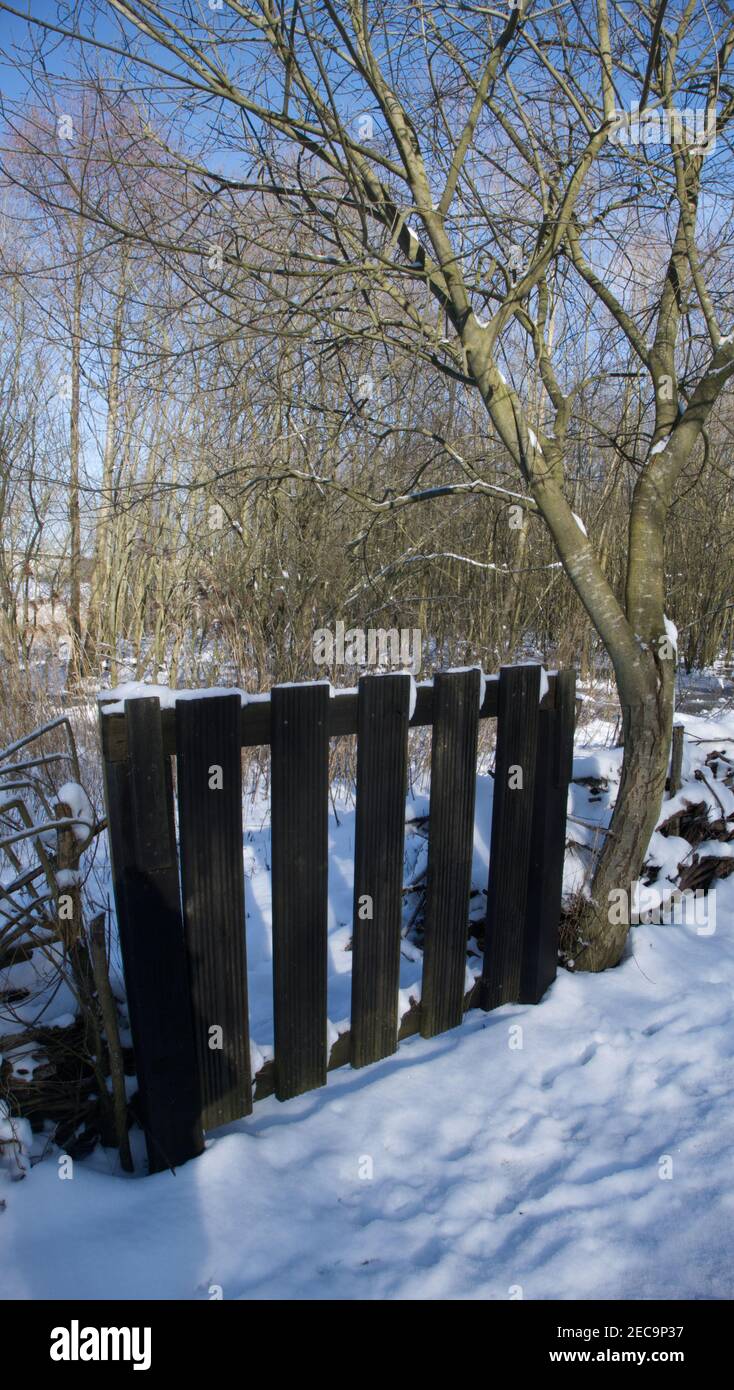 Scena di neve rurale con un cancello di legno marrone scuro. Foto Stock
