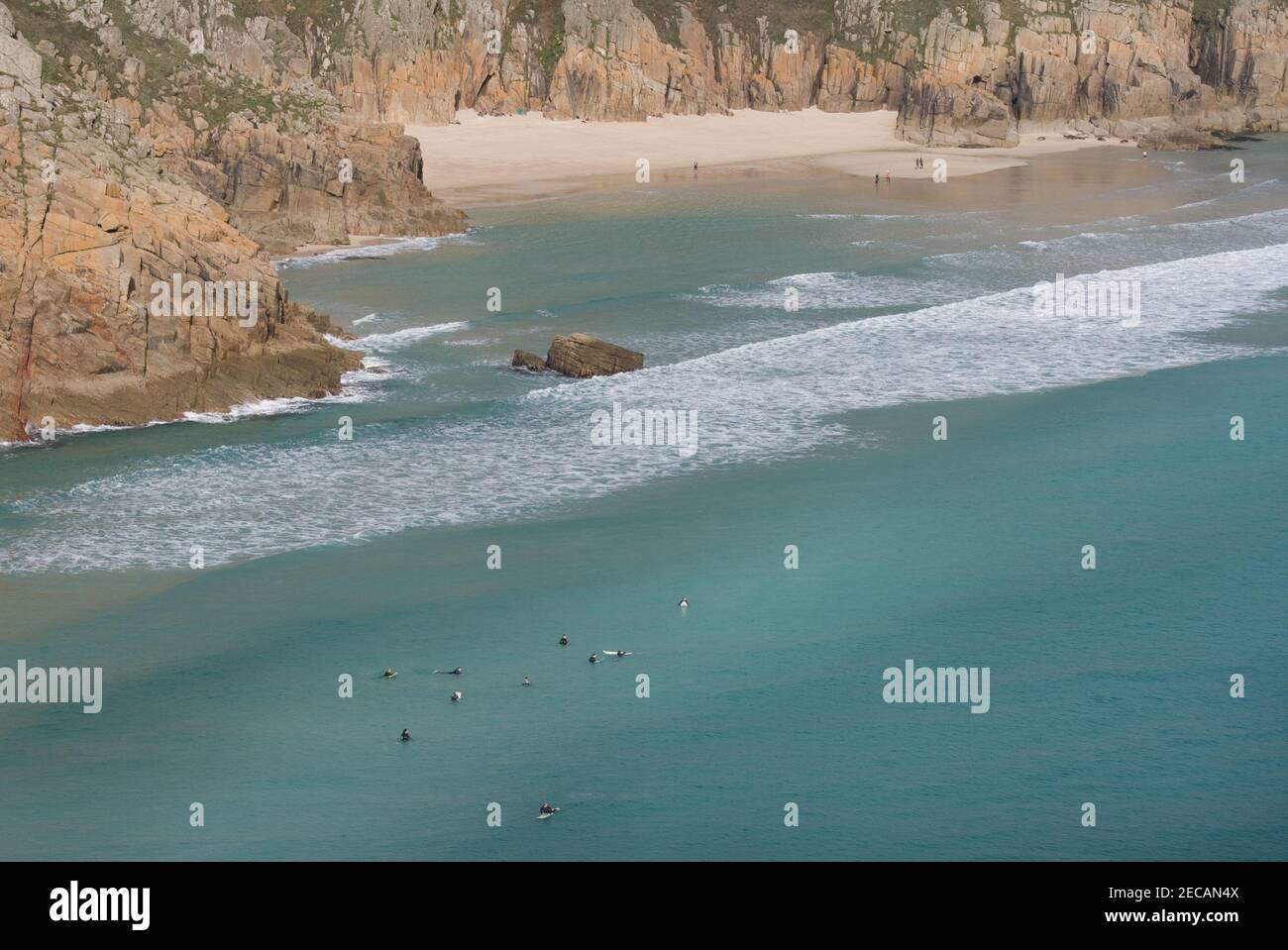 In attesa di grande surf a Porthcurno Cove; Pedn Vounder spiaggia in lontananza. Pedn Vounder è una spiaggia naturista non ufficiale. Penwith Peninsula, Cornovaglia. Foto Stock