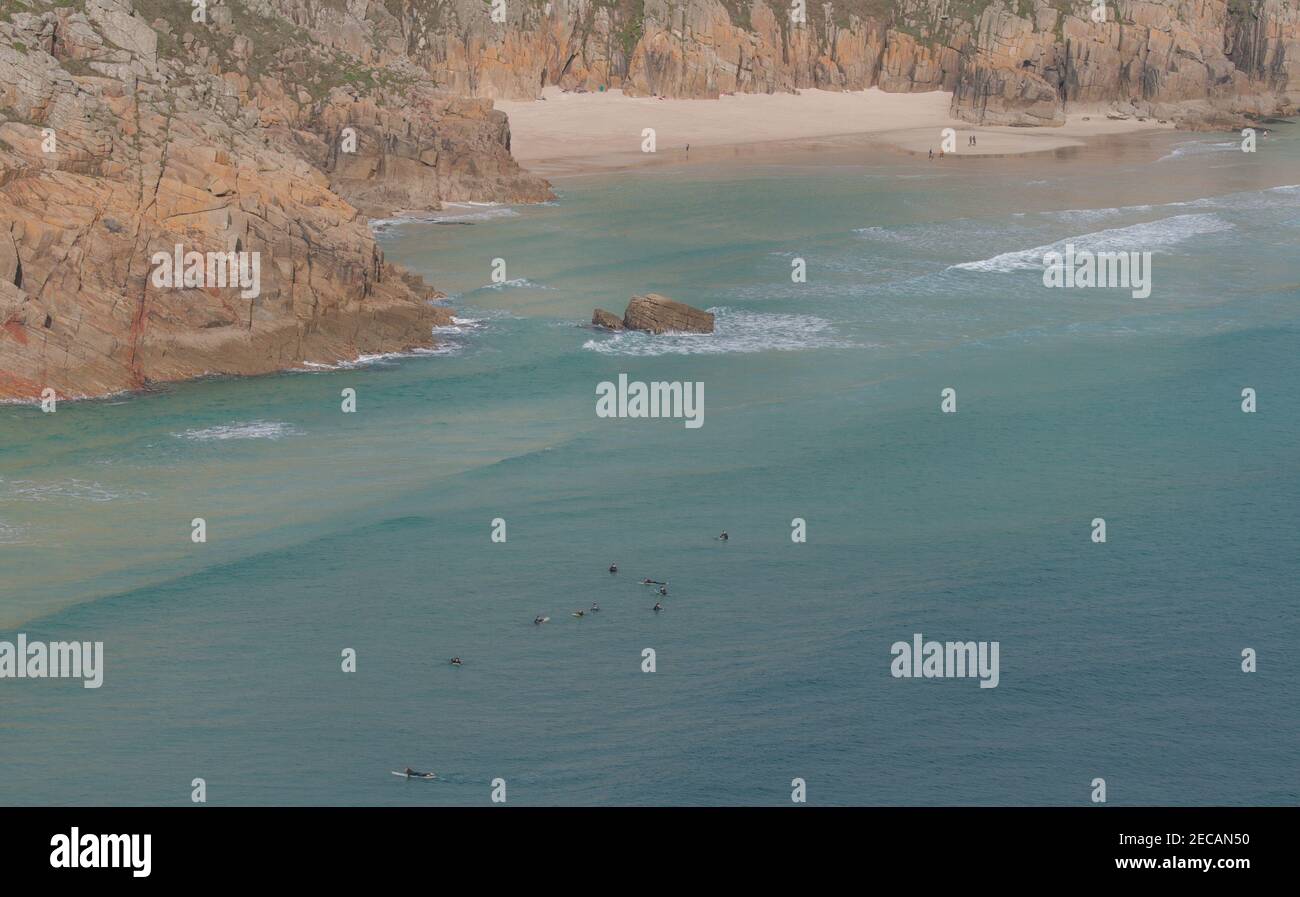 In attesa di grande surf a Porthcurno Cove; Pedn Vounder spiaggia in lontananza. Pedn Vounder è una spiaggia naturista non ufficiale. Penwith Peninsula, Cornovaglia. Foto Stock