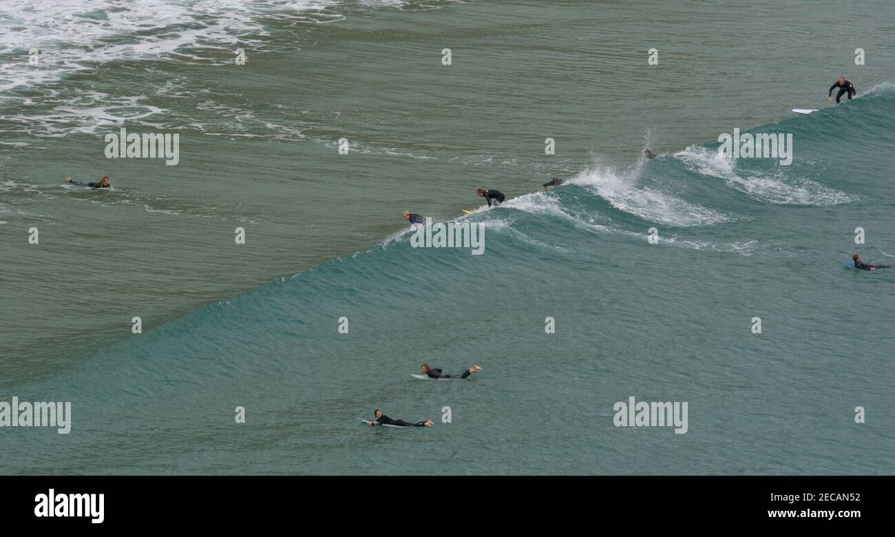 Surfers cattura un'onda al largo della spiaggia di Porthcurno, Penwith Peninsula, Cornovaglia Foto Stock