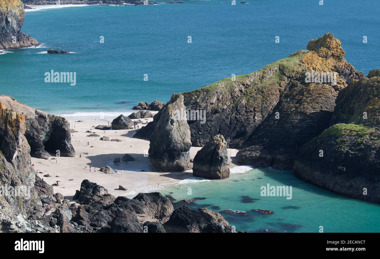 Sabbia bianca e mare azzurro a Kynance Cove sulla penisola di Lizard, Cornovaglia. A bassa marea le persone possono accedere alla spiaggia, ma l'alta marea copre tutto. Foto Stock