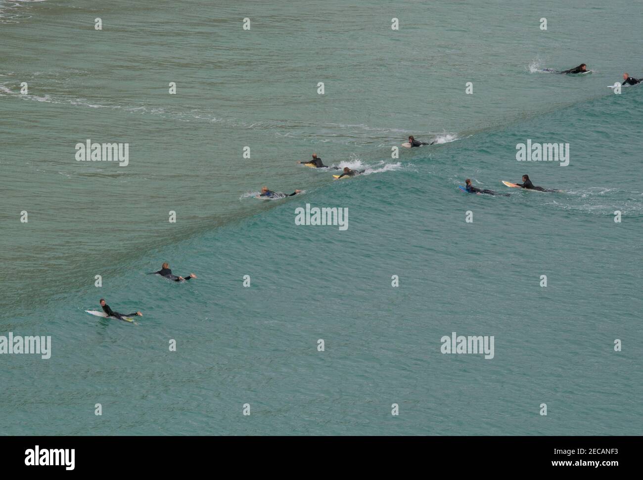 Surfers cattura un'onda al largo della spiaggia di Porthcurno, Penwith Peninsula, Cornovaglia Foto Stock