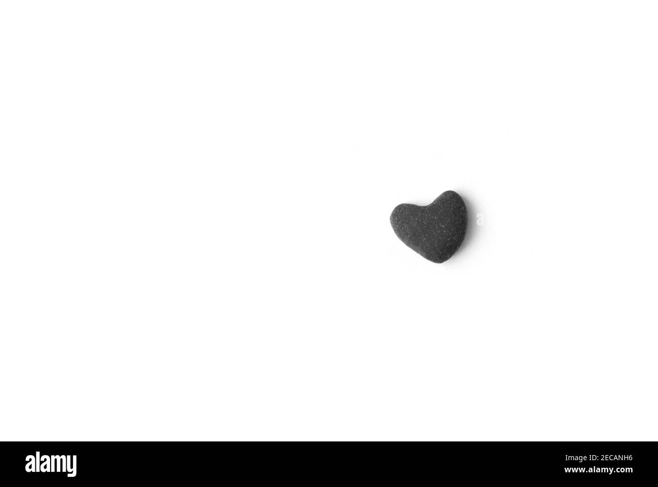 Piccola pietra grigia a forma di cuore su sfondo bianco. Foto Stock