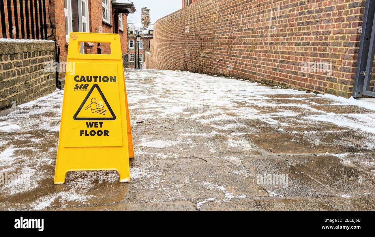 Un cartello di attenzione sul pavimento bagnato che segnala il pericolo di  scivolamento su un percorso ghiacciato Foto stock - Alamy