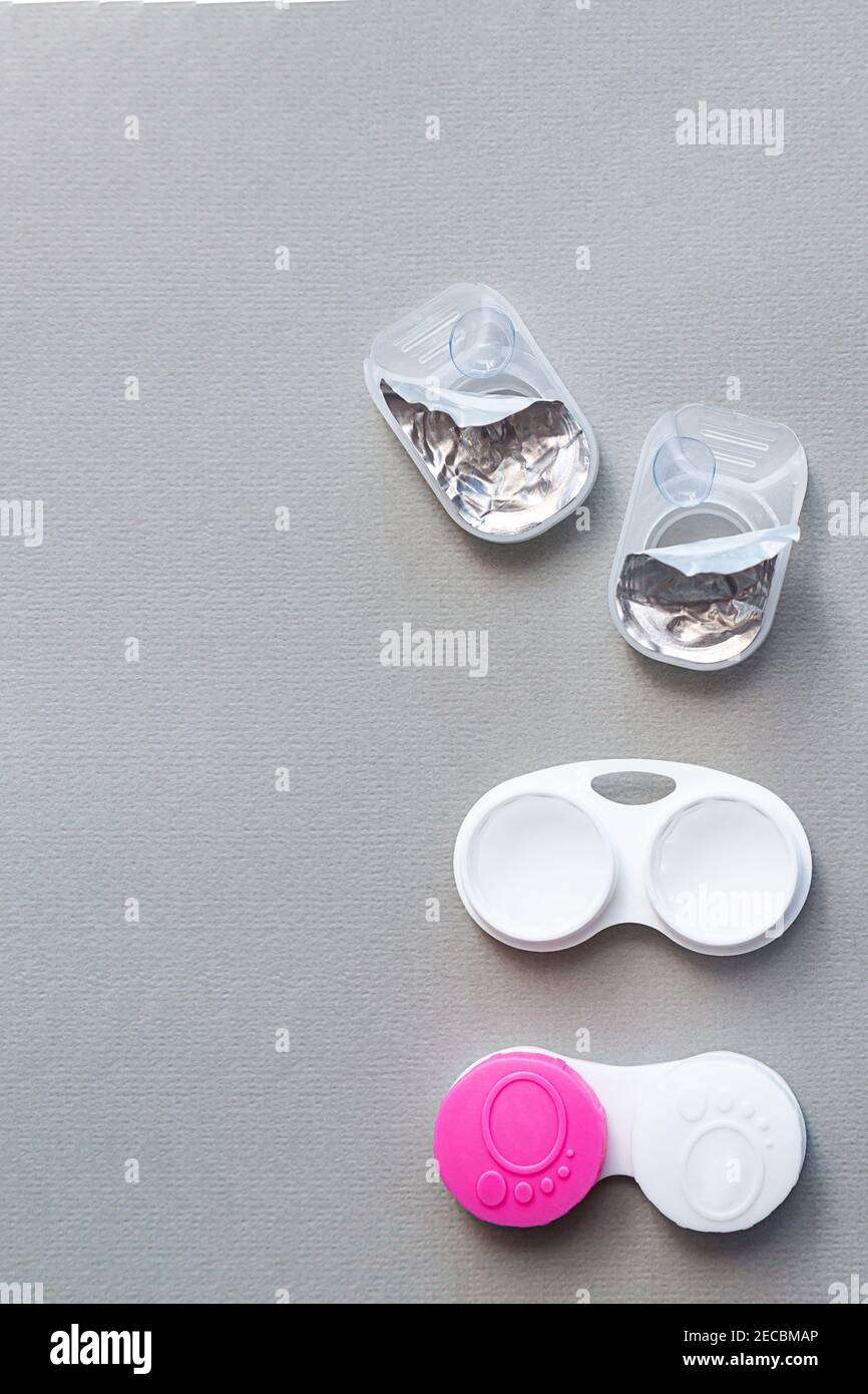 Le lenti a contatto e gli accessori sono piatti su uno sfondo grigio. Composizione con custodia per obiettivo, spazio per la copia Foto Stock