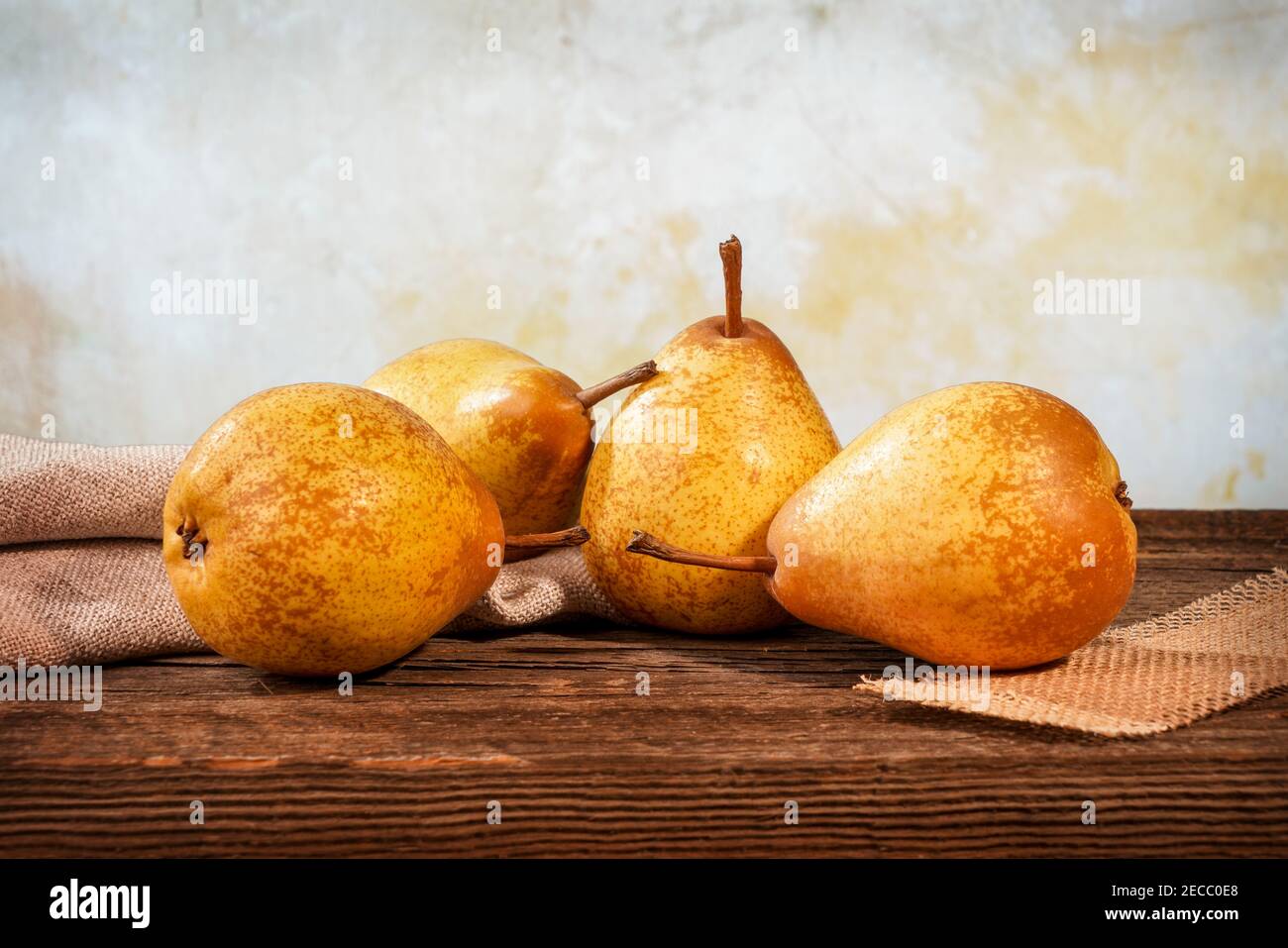 quattro pere gialle e una felce su un bosco di fienile tavolo davanti a uno sfondo Foto Stock