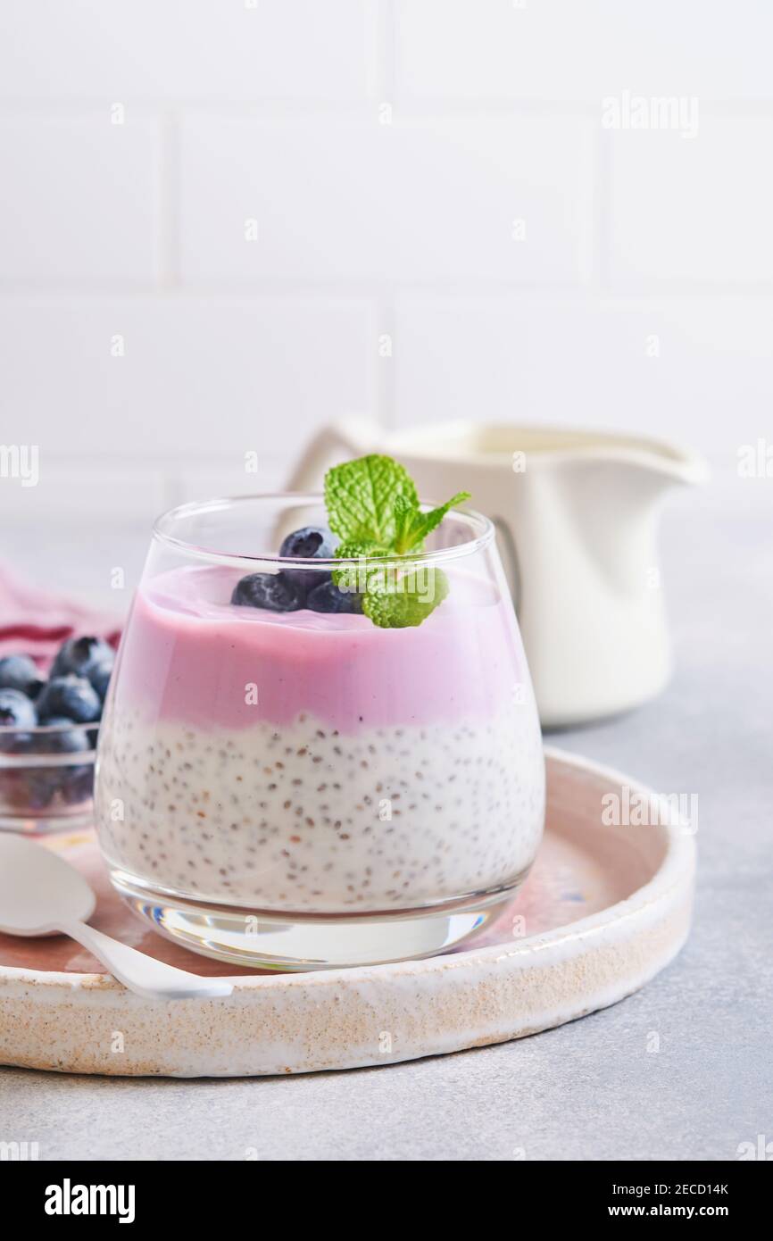 Budino di semi di Chia con yogurt al mirtillo e frutti di bosco freschi in vetro preparati per una sana colazione. Messa a fuoco selettiva. Foto Stock