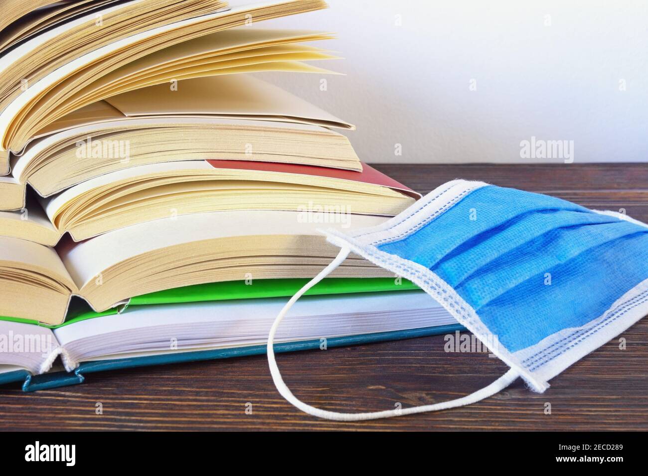 Libri aperti e maschera protettiva per il viso. Educazione durante il covid-19 pandemia, concetto. Messa a fuoco selettiva. Spazio di copia Foto Stock