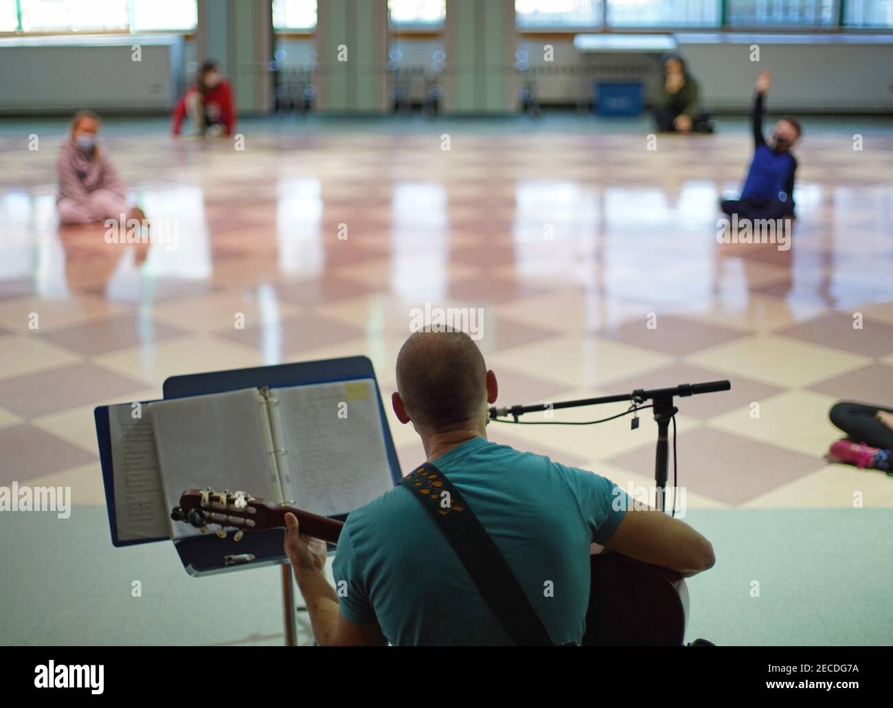 A causa dello sforzo di limitare il movimento degli studenti, e di limitare l'uso di spazi condivisi chiusi, un insegnante di musica conduce le sue lezioni di musica nella lar Foto Stock