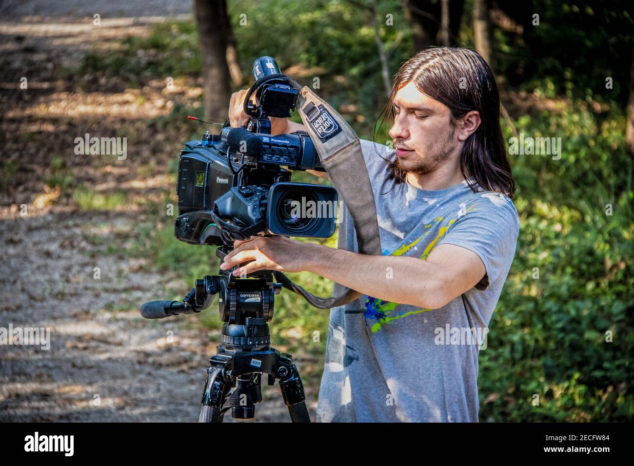 09 19 2019 Tulsa USA fotogiornalista maschile vestito casualmente assembla la macchina fotografica per l'intervista con alberi sfocati in background. Foto Stock
