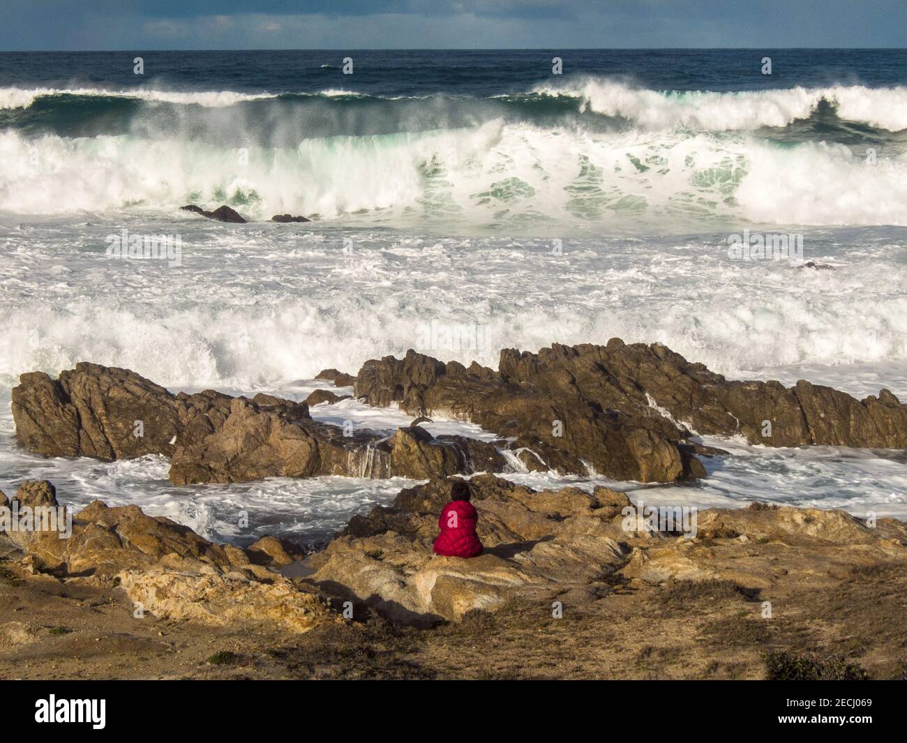 La donna Lone affronta una grande ondata lungo la costa californiana della baia di Monterey Foto Stock