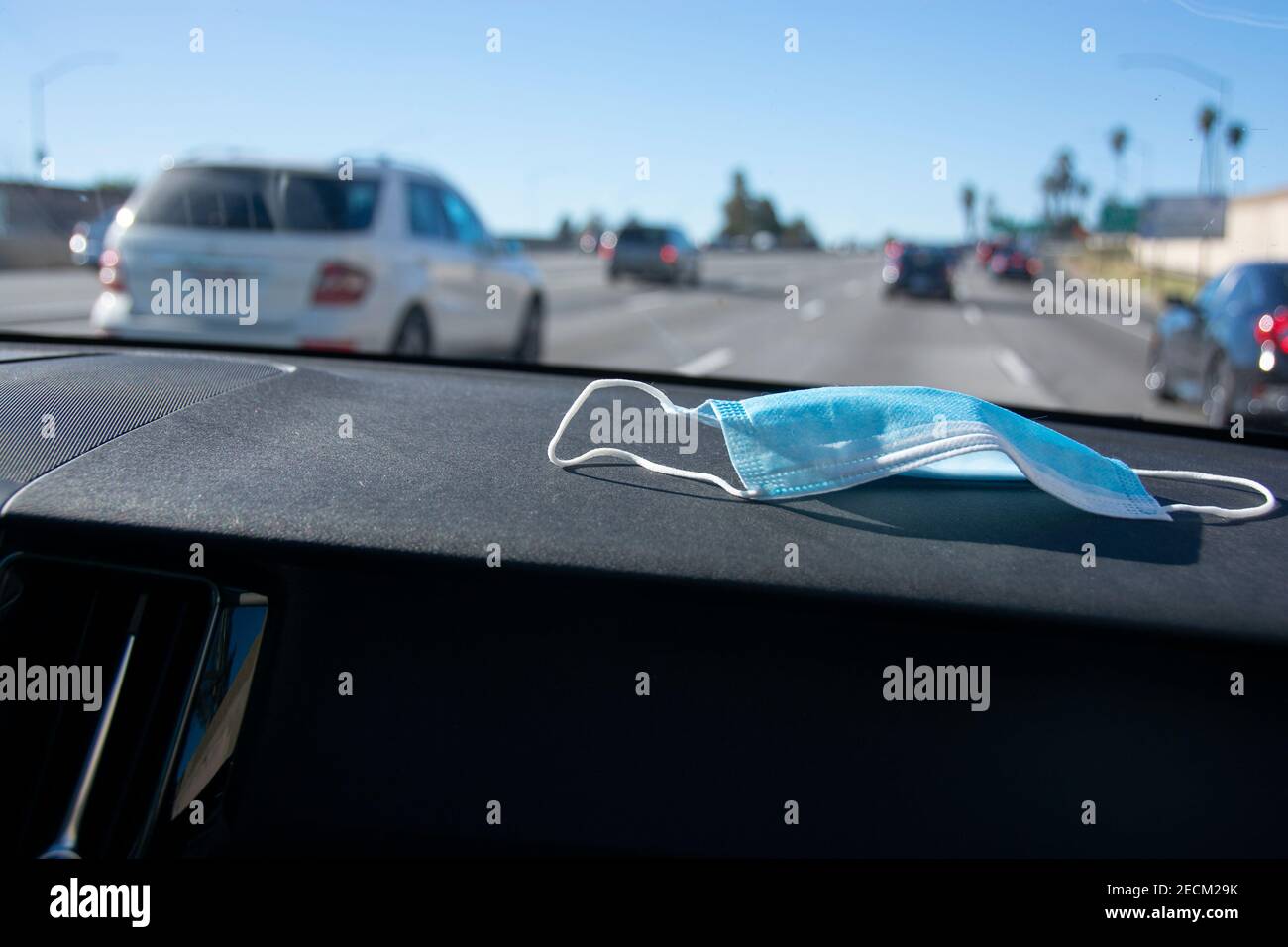 Una maschera si siede sul cruscotto di un'auto mentre naviga lungo la superstrada 5 in direzione di Los Angeles. Foto Stock