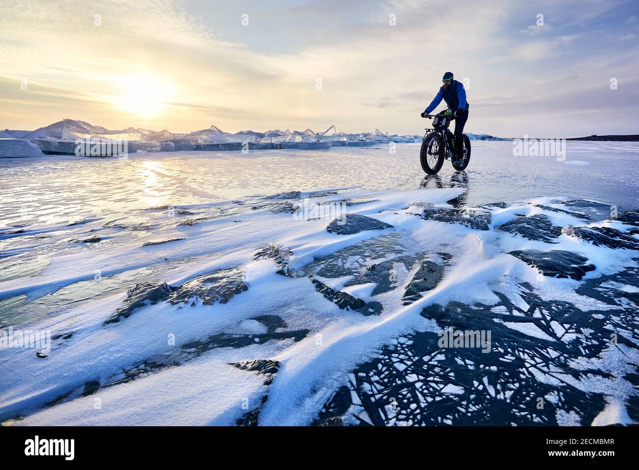 L'uomo fa un giro in bici grasso al lago ghiacciato Kapchagay al tramonto In Kazakistan Foto Stock