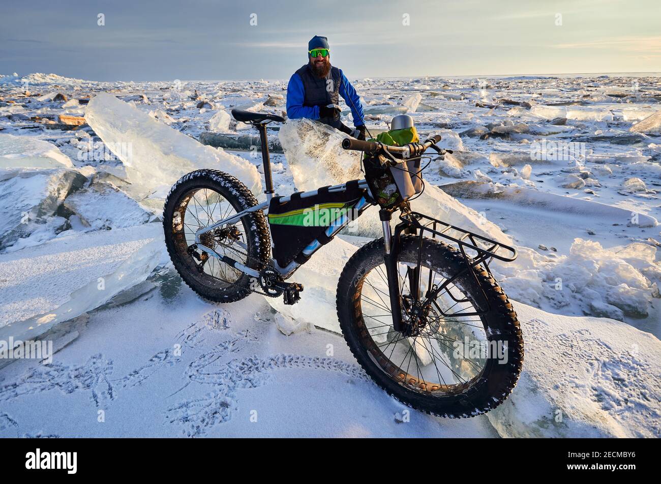 Uomo vicino alla bicicletta al lago ghiacciato al tramonto in Kazakistan Foto Stock