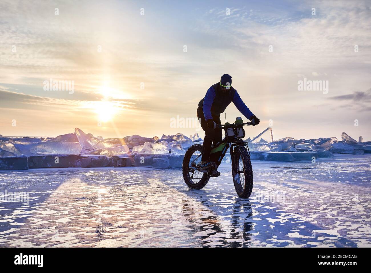 L'uomo si gira a Fat bike sul lago ghiacciato Kapchagay al tramonto in Kazakistan Foto Stock