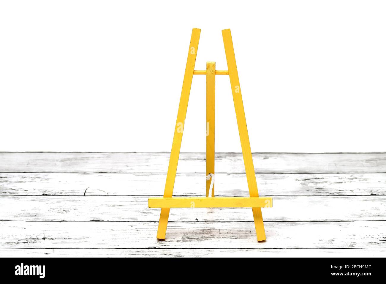 Piccolo cavalletto in legno su un tavolo di legno con grunge bianco Foto Stock