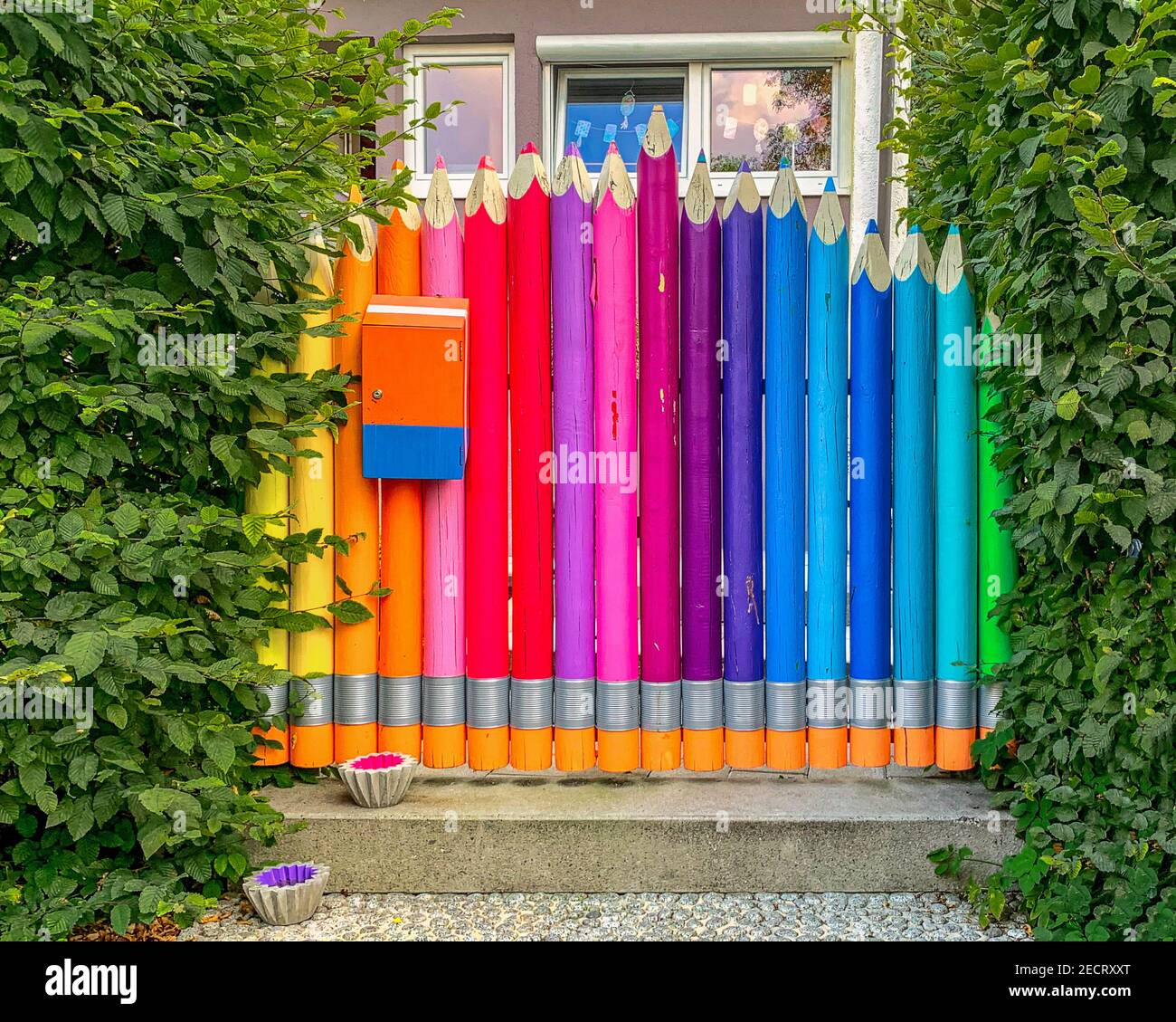 Meravigliosa porta d'ingresso color arcobaleno incorniciata da siepe verde. Foto Stock