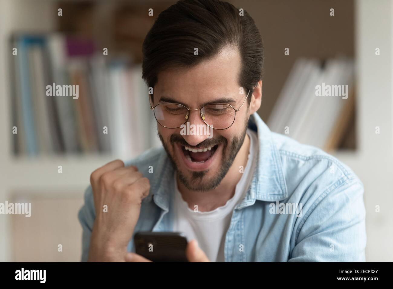 L'uomo sopravorato guarda lo schermo del cellulare trionfa la lotteria vincente Foto Stock