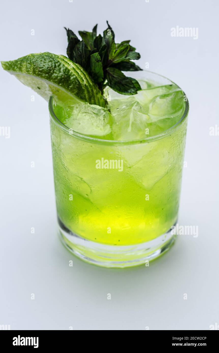 Un primo piano di un bicchiere di rinfrescante mojito cocktail con lime e menta su sfondo bianco Foto Stock