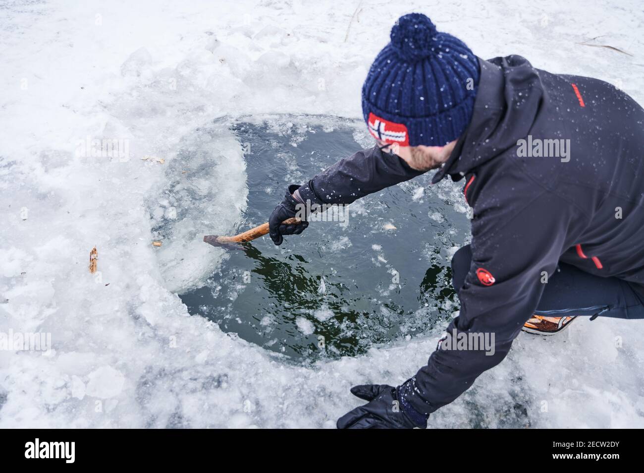 Berlino, Germania. 14 Feb 2021. Il bagnino di ghiaccio Mario spinge il cerchio battuto di ghiaccio giù con un hatchet. A temperature inferiori allo zero, entra in acqua tre volte di fila per un breve periodo, indossando un cappuccio e dei bauli da nuoto. Credit: Annette Riedl/dpa/Alamy Live News Foto Stock