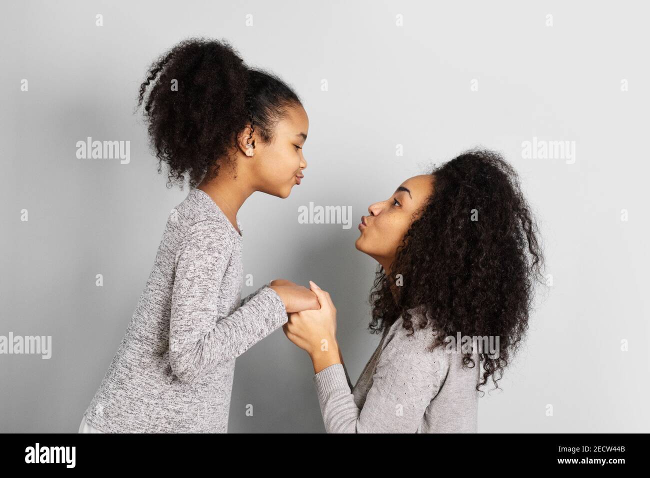 Madre afroamericana con sua figlia che si guarda l'un l'altro isolato su sfondo grigio neutro. Foto Stock