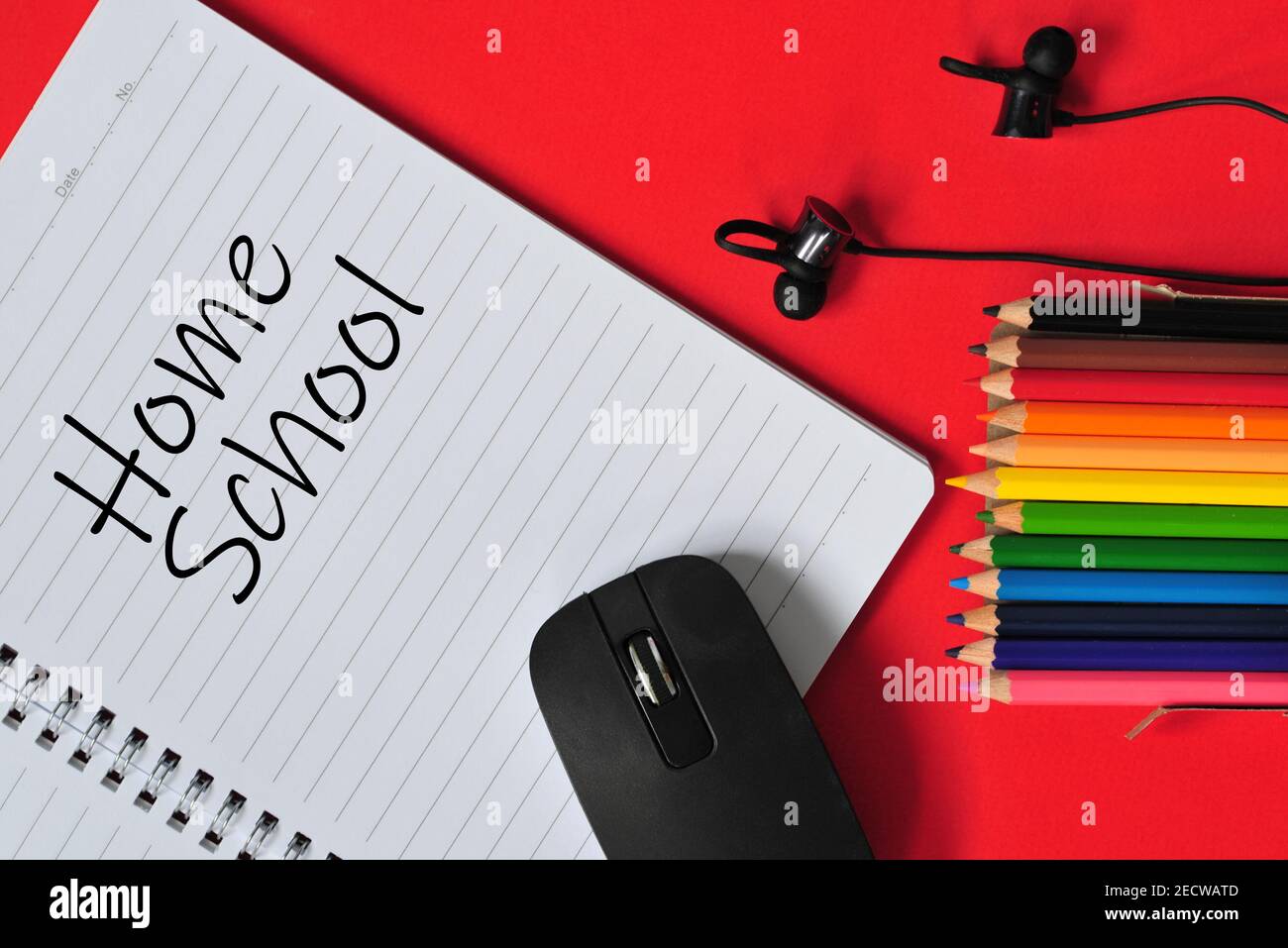 Concetto di educazione in riferimento all'apprendimento online. Mouse, auricolari, notebook, matite colorate con testo "Home School". Punti di messa a fuoco selettivi Foto Stock