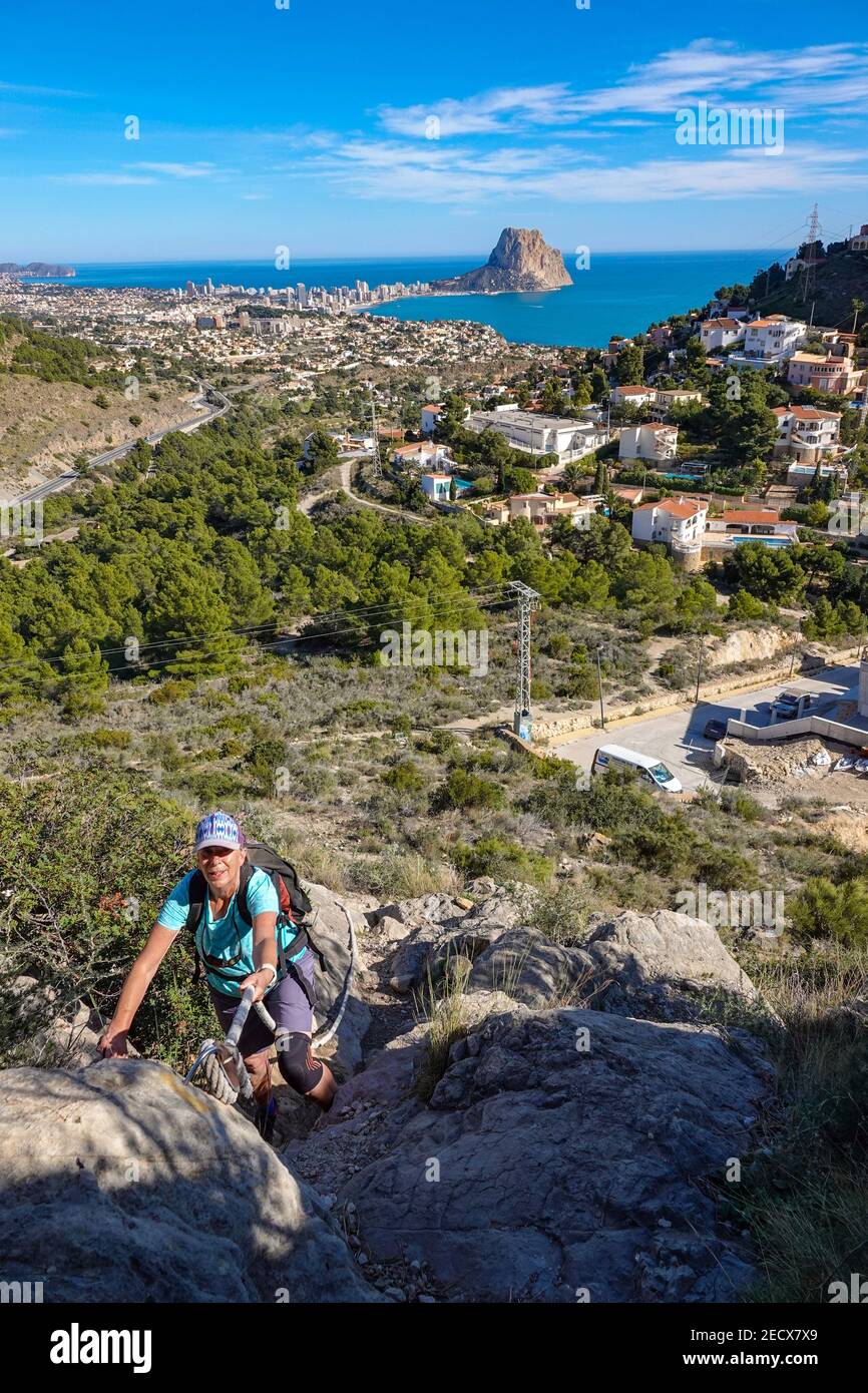 Femmina che scrambling su Castell de Calp difesa, sopra Mascarat Gorge, Sierre de Toix, Calpe, Costa Blanca, Spagna Foto Stock