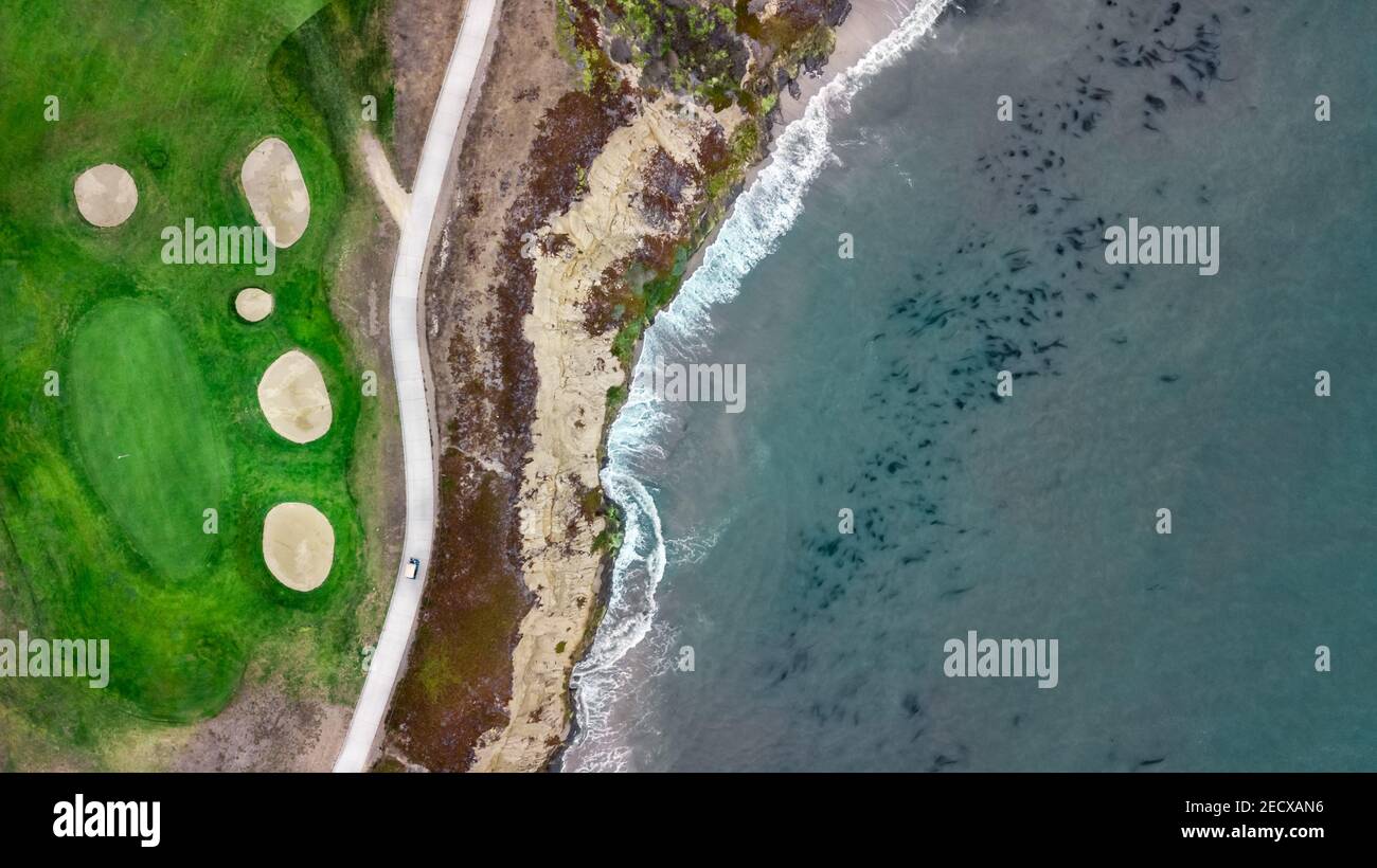 Vista sul drone di un bellissimo campo da golf accanto all' ocean con le onde che colpiscono la riva in California Foto Stock