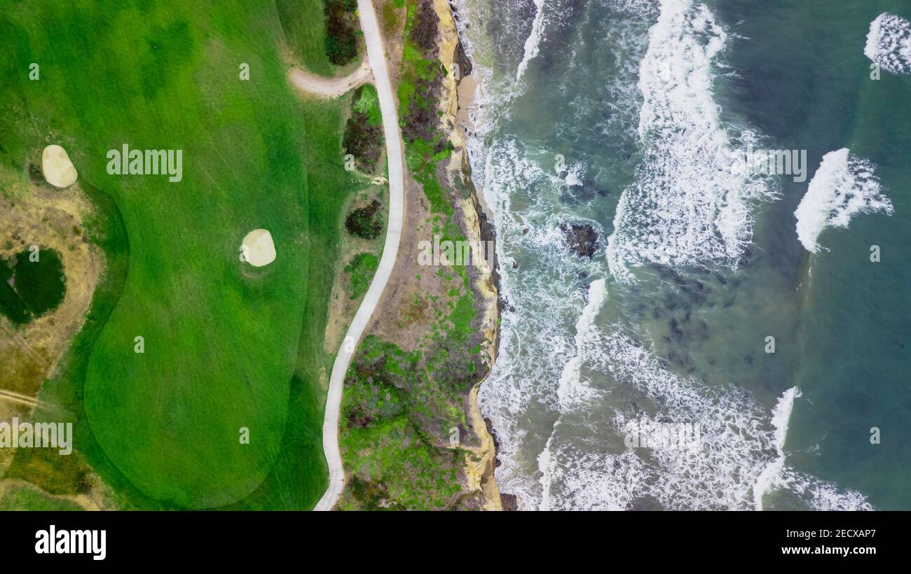 Vista sul drone di un bellissimo campo da golf accanto all' ocean con le onde che colpiscono la riva in California Foto Stock