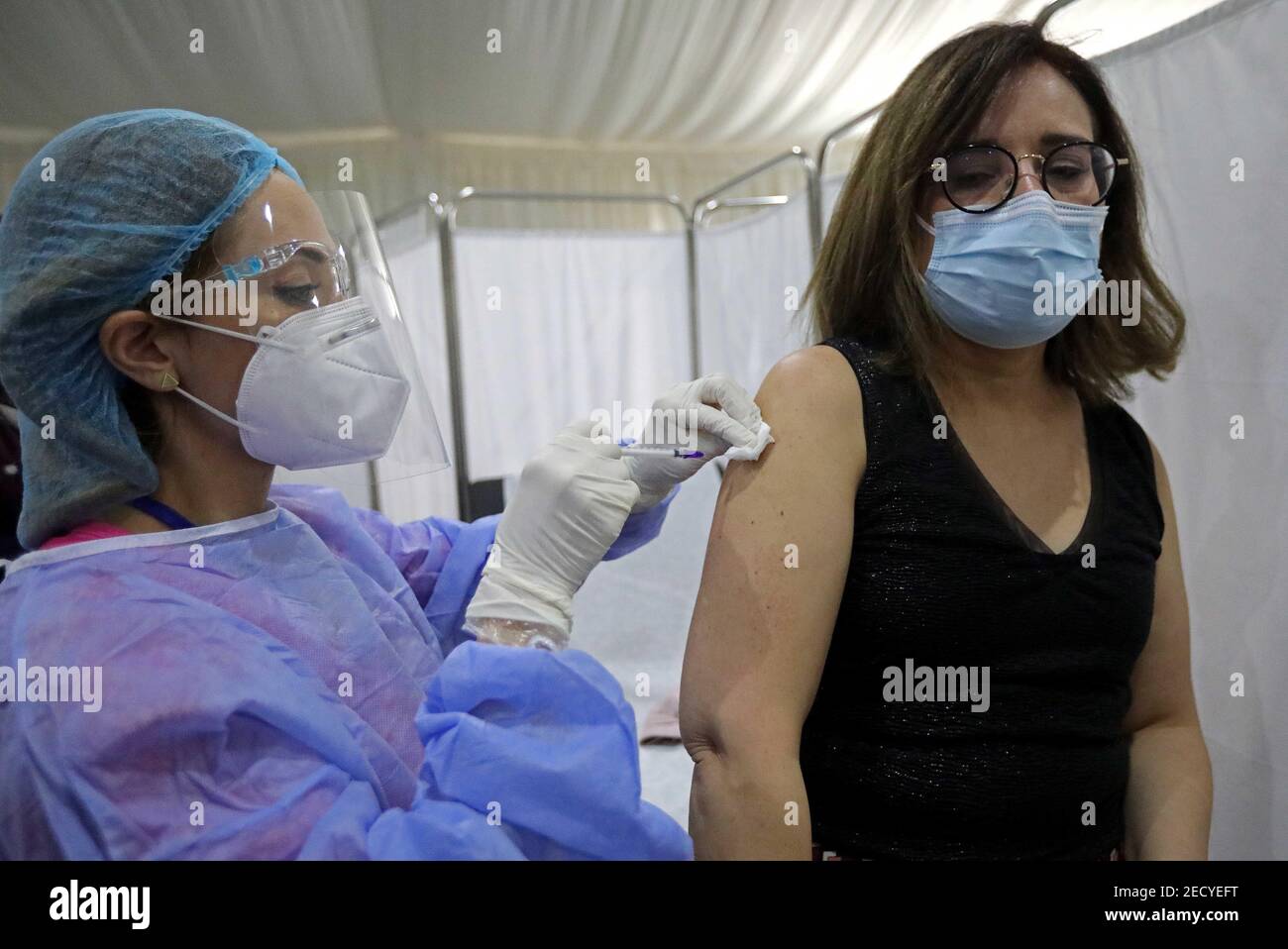 Beirut, Libano. 14 Feb 2021. Un membro del personale del Saint George Hospital riceve una dose di vaccino contro COVID-19 a Beirut, Libano, il 14 febbraio 2021. Il Libano ha lanciato domenica la sua campagna di vaccinazione iniziando con i dipendenti nel settore sanitario dopo aver ricevuto, un giorno prima, 28,500 vaccini da Pfizer-BioNTech, LBCI canale TV locale riferito. Credit: Bilal Jawich/Xinhua/Alamy Live News Foto Stock