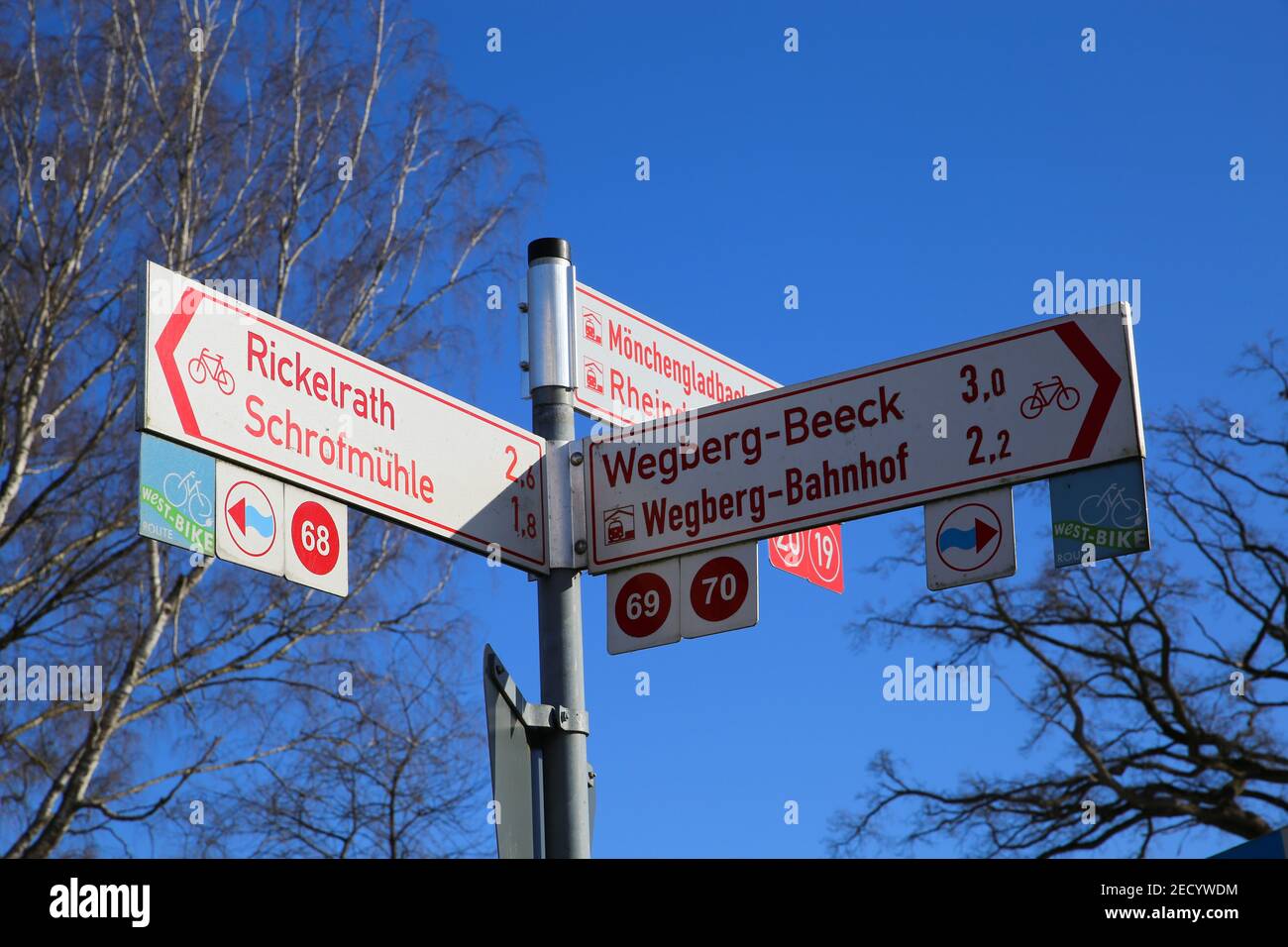 Wegberg, Germania - 9 febbraio. 2021: Vista ad angolo basso sui cartelli di direzione della pista ciclabile contro il cielo blu in inverno (messa a fuoco sul segnale destro) Foto Stock