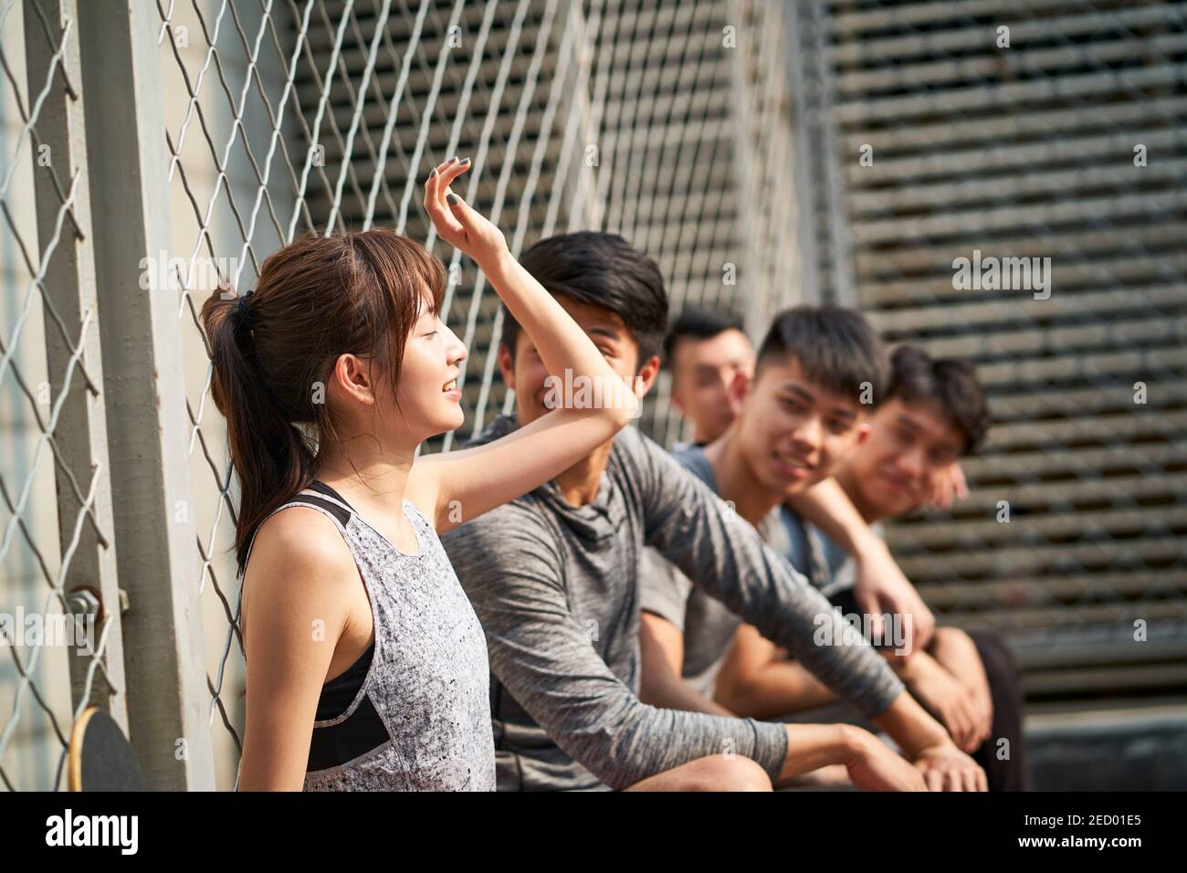 giovani adulti asiatici hipster riposarsi all'aperto in un campo di pallacanestro dopo l'esercizio Foto Stock