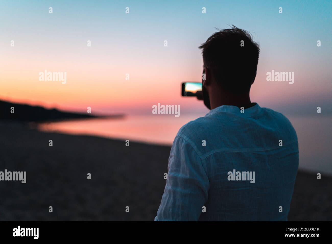 Uomo che fa foto in spiaggia al tramonto durante l'oro ora Foto Stock